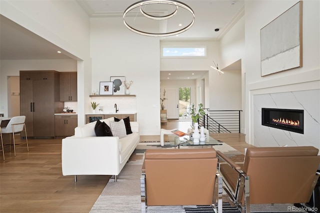 living room with sink, a towering ceiling, a fireplace, and light hardwood / wood-style flooring