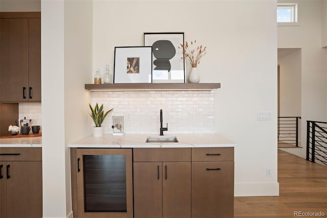 bar featuring hardwood / wood-style floors, backsplash, beverage cooler, and sink