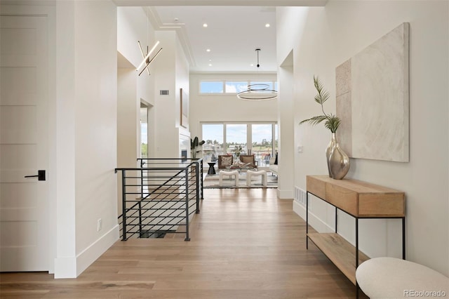 foyer featuring light wood-type flooring, ornamental molding, and a high ceiling