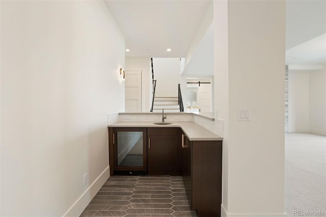 bar featuring dark brown cabinetry, sink, and dark carpet