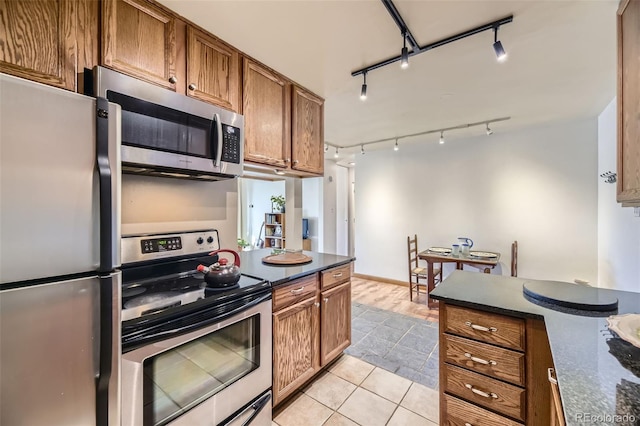 kitchen featuring stainless steel appliances, dark stone counters, and light tile patterned flooring