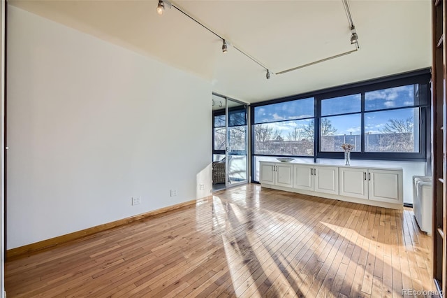 unfurnished room featuring rail lighting and light hardwood / wood-style flooring