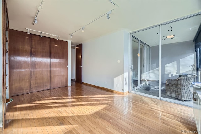 empty room with rail lighting and hardwood / wood-style floors