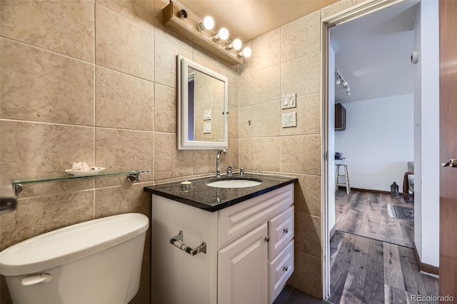 bathroom with tile walls, toilet, wood-type flooring, and vanity