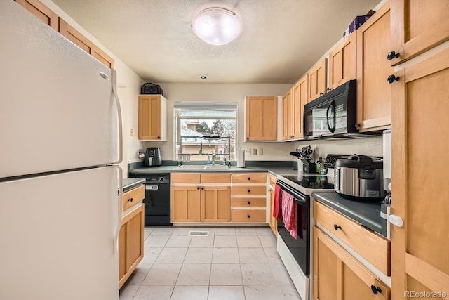 kitchen with light brown cabinets, a sink, visible vents, and black appliances