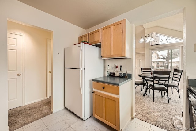 kitchen featuring dark countertops, light colored carpet, freestanding refrigerator, vaulted ceiling, and a chandelier