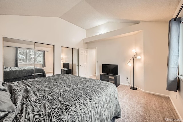 carpeted bedroom featuring lofted ceiling, a textured ceiling, baseboards, and two closets