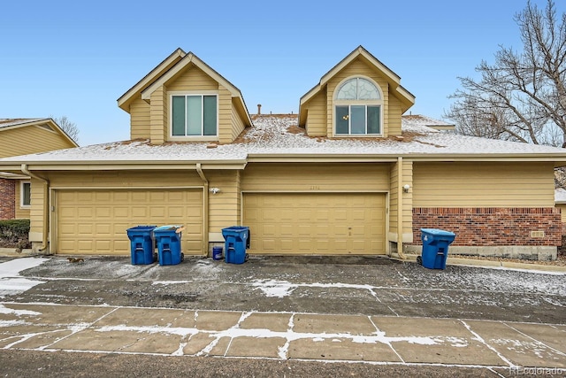 view of front of home with an attached garage, driveway, and brick siding