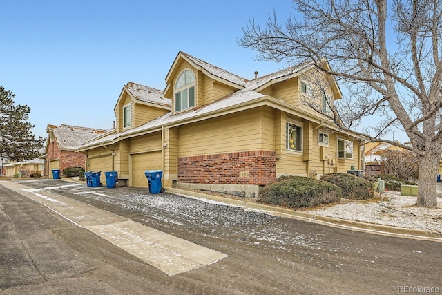 view of side of property with a garage, concrete driveway, and brick siding