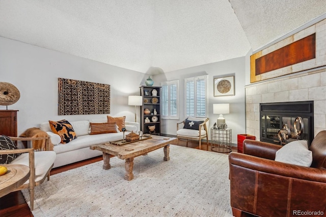 living room with a fireplace, hardwood / wood-style floors, a textured ceiling, and vaulted ceiling