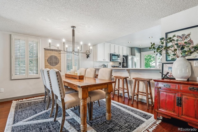 dining space featuring a textured ceiling, dark hardwood / wood-style flooring, and a notable chandelier