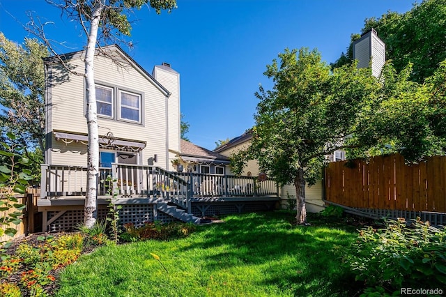 back of property with a deck and a lawn