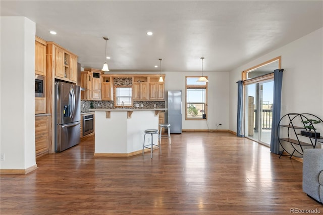 kitchen with hardwood / wood-style flooring, sink, a kitchen bar, a kitchen island, and appliances with stainless steel finishes