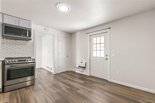 kitchen featuring heating unit, stainless steel appliances, white cabinetry, and dark wood-type flooring