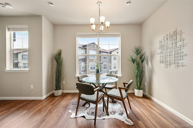 dining area featuring a wealth of natural light, wood finished floors, baseboards, and an inviting chandelier