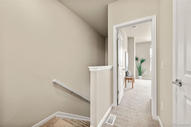 hall featuring light colored carpet, baseboards, visible vents, and an upstairs landing