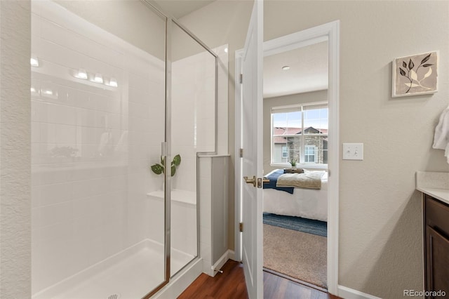 full bath featuring a stall shower, vanity, connected bathroom, and wood finished floors