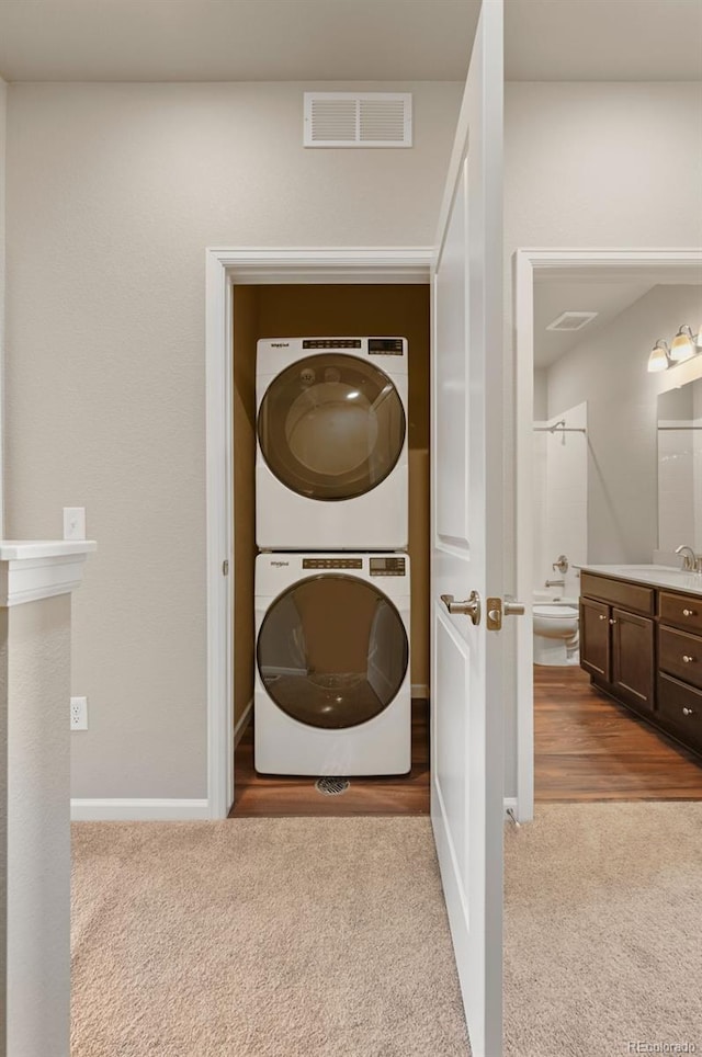 washroom with laundry area, stacked washer / dryer, visible vents, and light colored carpet