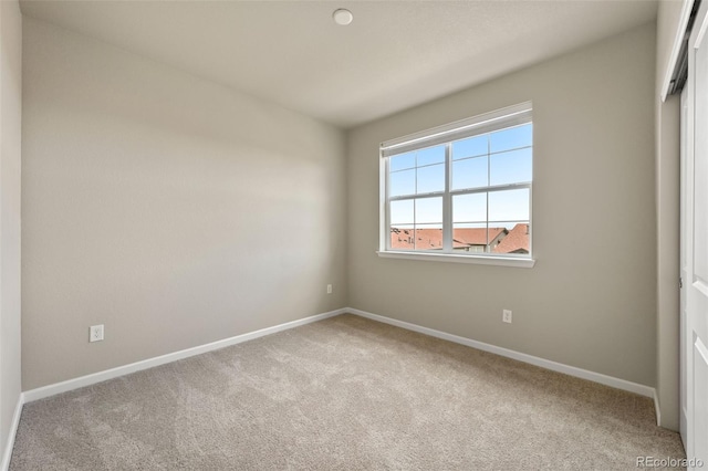 empty room featuring light colored carpet and baseboards