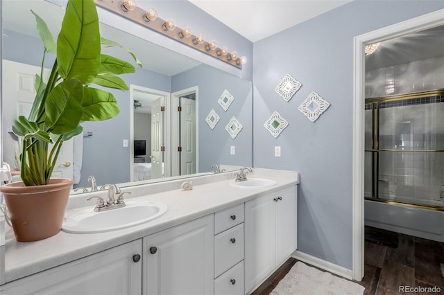 20182 E Maplewood Pl, Centennial, CO 80016 - bathroom featuring double vanity, wood finished floors, ensuite bath, combined bath / shower with glass door, and baseboards
