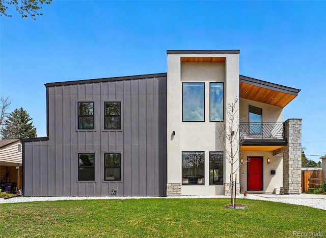 modern home featuring board and batten siding, a balcony, and a front yard