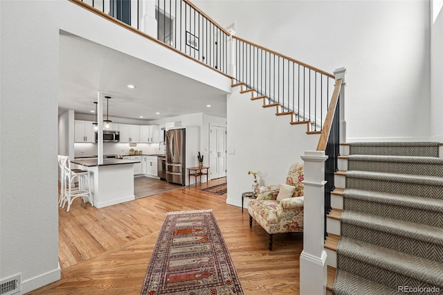 stairs with wood finished floors, recessed lighting, baseboards, and a towering ceiling
