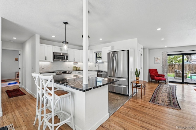 kitchen featuring appliances with stainless steel finishes, a sink, light wood-type flooring, white cabinetry, and recessed lighting