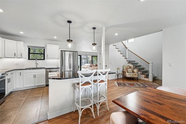 kitchen featuring appliances with stainless steel finishes, a sink, tasteful backsplash, a breakfast bar, and white cabinets