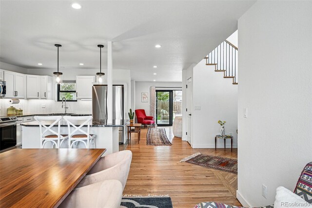 dining room with plenty of natural light, recessed lighting, light wood-style floors, and baseboards