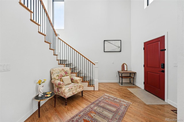 foyer entrance featuring a high ceiling, wood finished floors, stairs, and baseboards