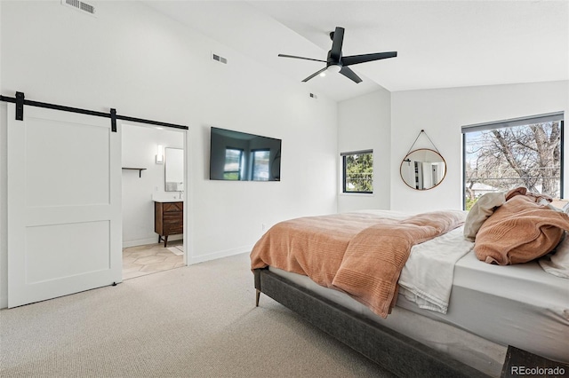 bedroom with a barn door, light carpet, high vaulted ceiling, baseboards, and ensuite bathroom