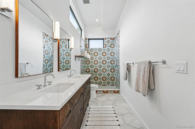 full bathroom featuring toilet, a stall shower, double vanity, tile patterned floors, and baseboards
