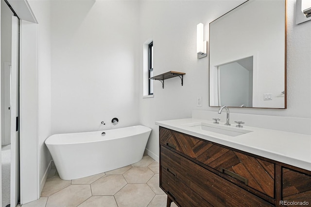 full bathroom featuring a freestanding tub, vanity, baseboards, and tile patterned flooring