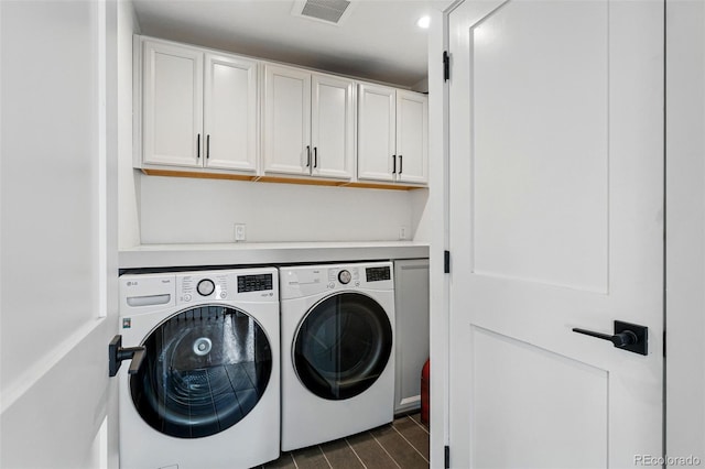 clothes washing area featuring independent washer and dryer, cabinet space, and dark wood-style floors