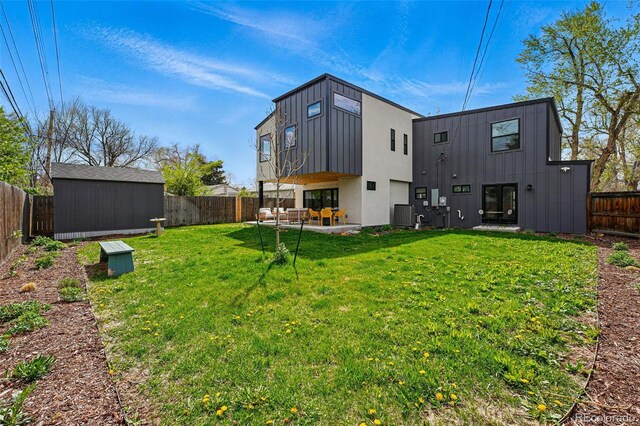 back of house with a storage shed, an outbuilding, a patio area, board and batten siding, and central air condition unit