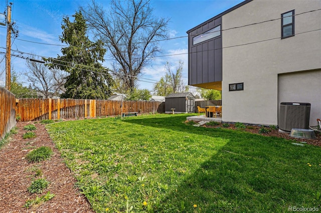 view of yard with central AC unit, a shed, an outbuilding, and a patio