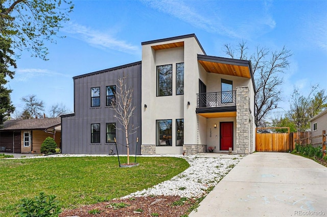 contemporary home with a balcony, stucco siding, and stone siding