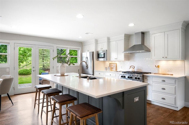 5586 Colorow Dr, Morrison, CO 80465 - kitchen with wall chimney range hood, appliances with stainless steel finishes, a sink, a breakfast bar, and recessed lighting