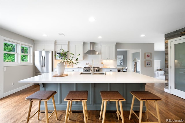 5586 Colorow Dr, Morrison, CO 80465 - kitchen featuring wall chimney range hood, appliances with stainless steel finishes, white cabinets, a spacious island, and recessed lighting