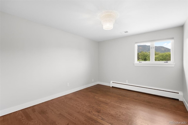 5586 Colorow Dr, Morrison, CO 80465 - spare room with baseboard heating, baseboards, dark wood-type flooring, and a chandelier