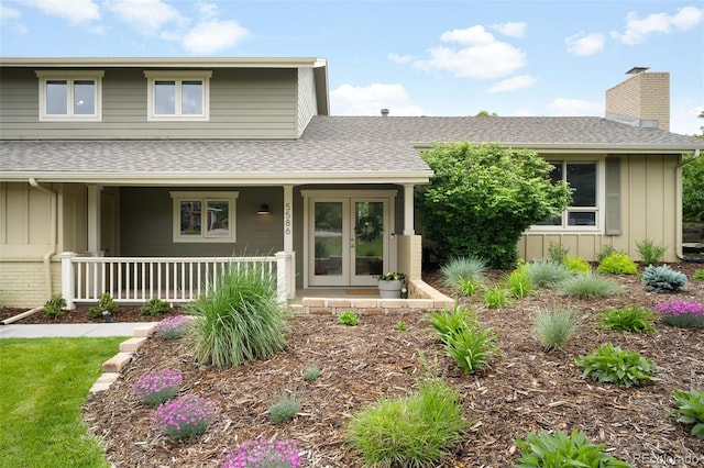 5586 Colorow Dr, Morrison, CO 80465 - view of front of home featuring board and batten siding, a shingled roof, covered porch, a chimney, and french doors