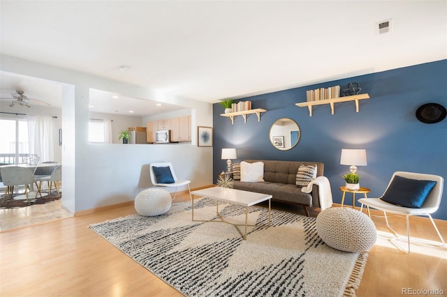 living room with ceiling fan and light hardwood / wood-style flooring