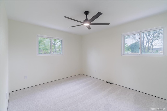 carpeted empty room with a ceiling fan and visible vents