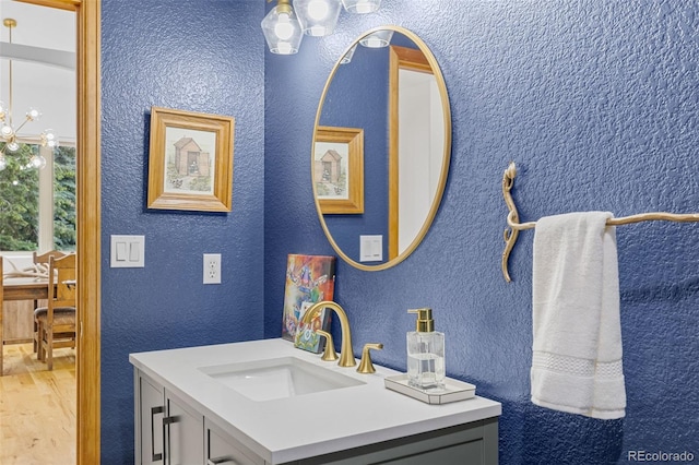 1474 Belford Ct, Evergreen, CO 80439 - bathroom featuring vanity, wood finished floors, a chandelier, and a textured wall