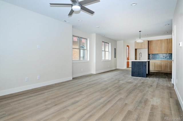 unfurnished living room featuring ceiling fan, sink, and light hardwood / wood-style flooring