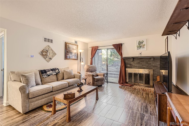 living area featuring a brick fireplace, visible vents, and a textured ceiling