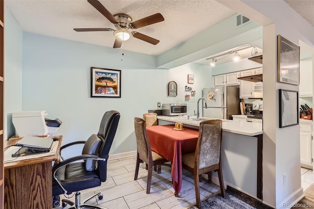 office area with baseboards, visible vents, a ceiling fan, a textured ceiling, and a sink