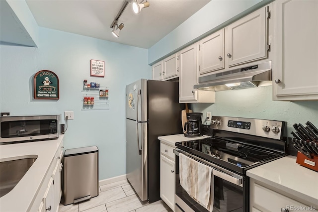 kitchen featuring appliances with stainless steel finishes, rail lighting, light countertops, under cabinet range hood, and white cabinetry