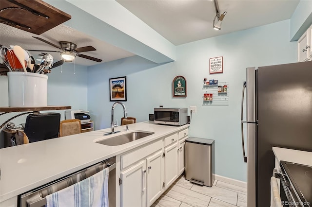 kitchen with stainless steel appliances, light countertops, white cabinets, and a sink