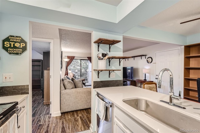 kitchen featuring open shelves, stainless steel dishwasher, white cabinetry, a sink, and a textured ceiling